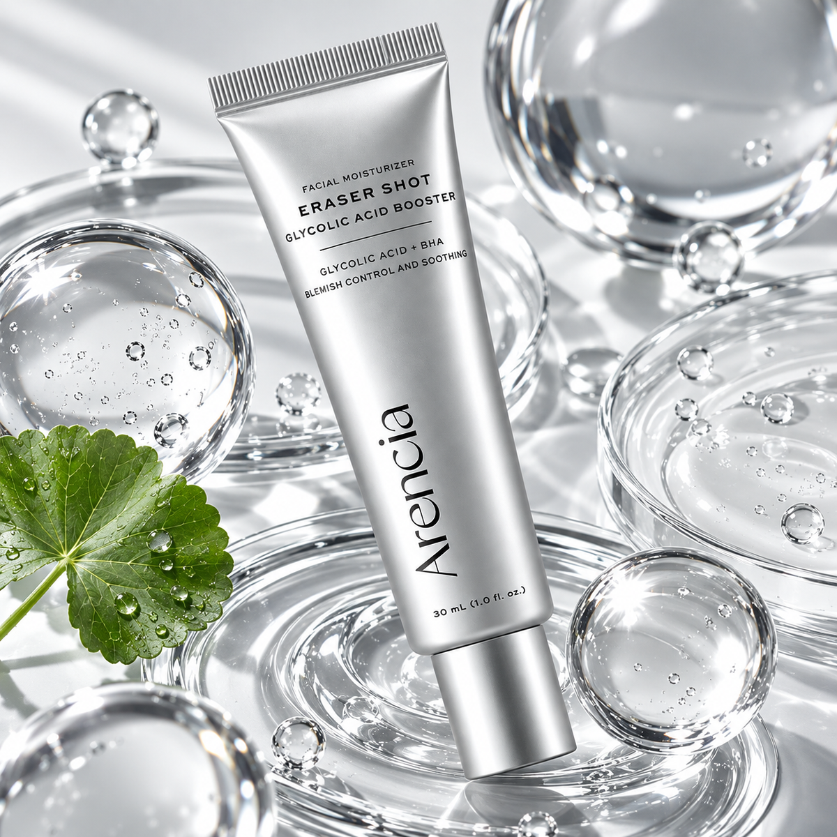 ARENCIA Eraser Shot Glycolic Acid Booster 30 ml – srebrna tuba korejske kreme okružena staklenim kuglama, kapljicama vode i zelenim listom