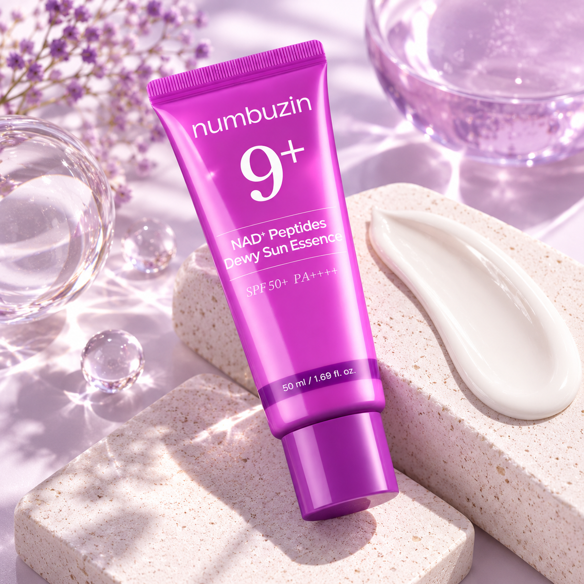 numbuzin No.9 Dewy Sun Essence 50 ml – ljubičasto pakovanje na svijetloj podlozi sa kremastom teksturom i dekorativnim staklenim kuglama